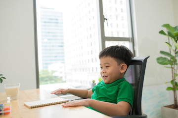 Head shot Portrait of happy asian cute child doing homework with smile face at home .