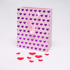 Concept on a white background of Saint Valentine heart of pink color on a package from the store.