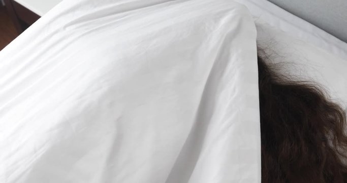 Sleepy woman then appearing from under blanket hardly waking up