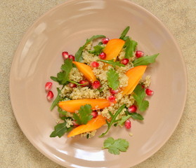 Quinoa salad with persimmon, pomegranate and fresh herbs, top view 
