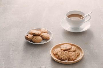 Cup of coffee with milk or cappuccino with cookies on light stone background. Drink with caffeine or cocoa with milk. Coffee break concept.