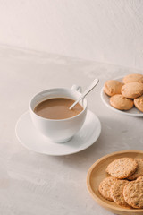 Cup of coffee with milk or cappuccino with cookies on light stone background. Drink with caffeine or cocoa with milk. Coffee break concept.