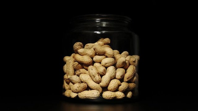Unpeeled peanuts disappearing from a glass jar - Stop Motion