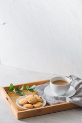 Closeup of coffee with milk in white cup and tasty cookies. Shot on light stone background