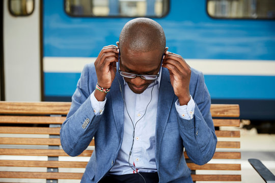 Businessman adjusting earphones at railway station