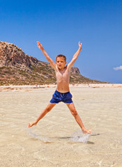 Obraz premium Boy jumping high on the beach. Balos bay, Crete, Greece.