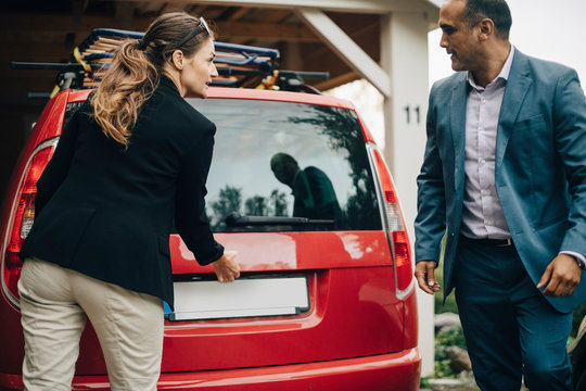 Businesswoman opening car trunk while looking at man