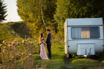 Wedding couple posing with camper van in forest