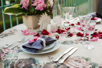 Wedding, anniversary, valentine romantic decor of the festive table in the restaurant with candles, flowers, peonies, rose petals, branches, empty wine glasses on old vintage table