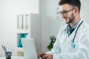 Portrait of Young Doctor on the Job working on laptop