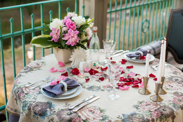 Wedding, anniversary, valentine romantic decor of the festive table in the restaurant with candles, flowers, peonies, rose petals, branches, empty wine glasses on old vintage table