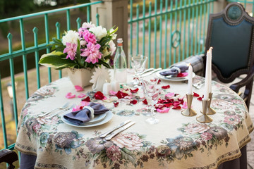 Wedding, anniversary, valentine romantic decor of the festive table in the restaurant with candles, flowers, peonies, rose petals, branches, empty wine glasses on old vintage table © mat_mary