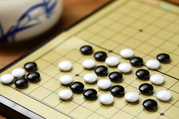 Chinese go game board, close up view of playing black and white stone pieces