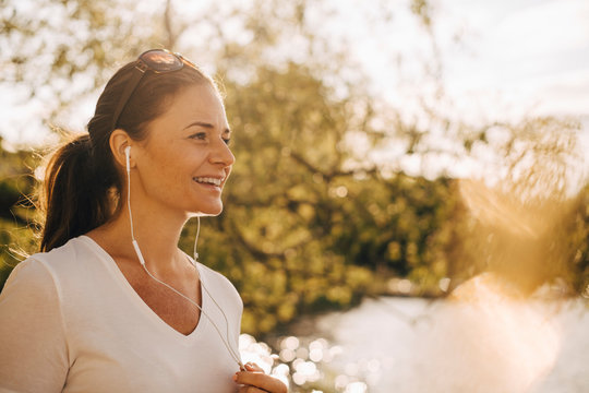 Smiling woman with earphone talking outdoors