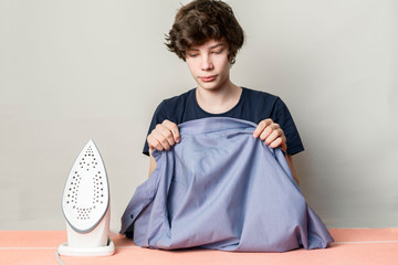 teenager stroking ironing his shirt before going to school
