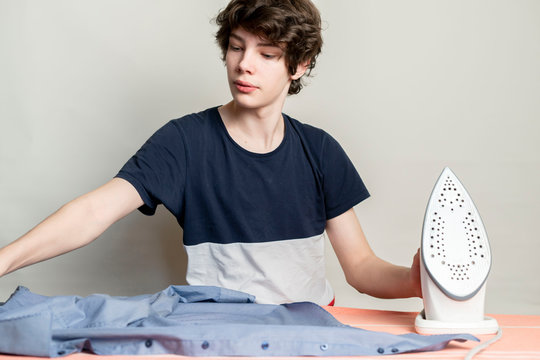 Teenager Stroking Ironing His Shirt Before Going To School