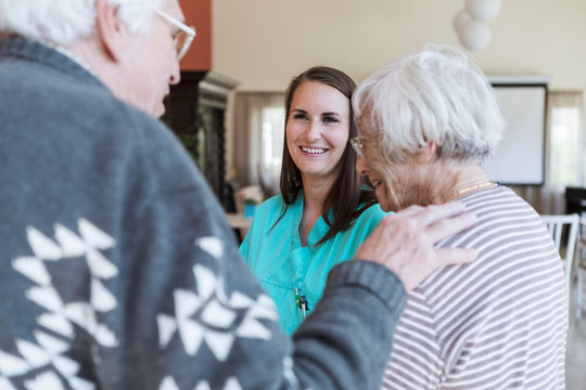 Smiling nurse looking at senior couple at home