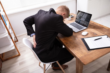 Man Having Backpain Working On Laptop In Office