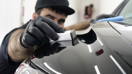 Professional ceramics handler apply different layers to the car using an applicator (sponge, fiber) immediately checking the effect. Concept from: Autodetailing, Special Ceramics, Nano technology. - Powered by Adobe