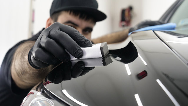 Professional ceramics handler apply different layers to the car using an applicator (sponge, fiber) immediately checking the effect. Concept from: Autodetailing, Special Ceramics, Nano technology.