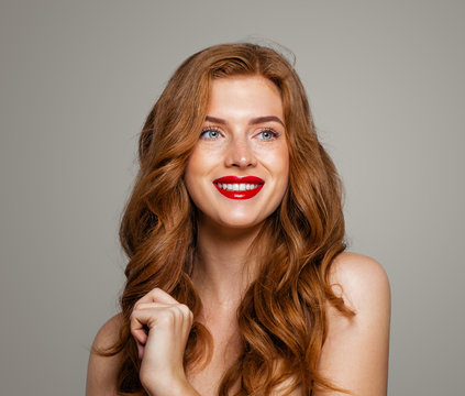 Happy redhead woman smiling. Excited red head girl with curly hairstyle. Ginger hair, cute smile, red lips makeup. Natural authentic beauty