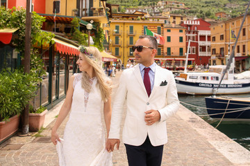 Fashion wedding couple posing on dock near sea port in Italy