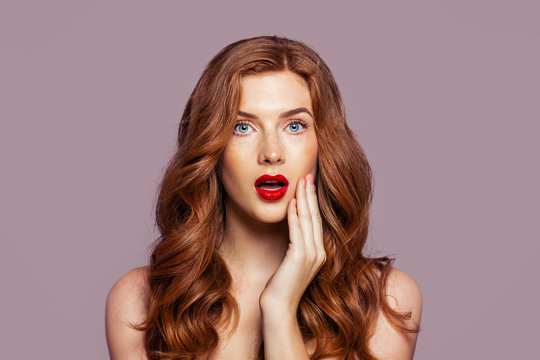 Surprised woman with beautiful red hair on bright pink background. Redhead girl with opened mouth portrait