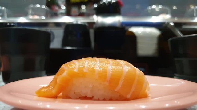 piece of salmon sushi in conveyor belt japanese restaurant
