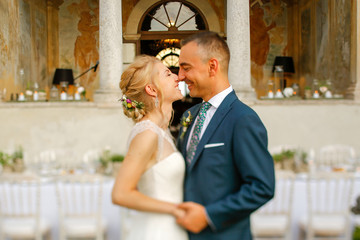 Wedding couple. Blonde bride and groom walking near old castle and garden