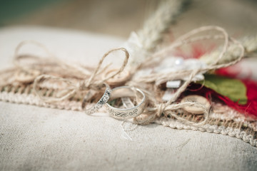 Wedding rings placed on a vintage decor of burlap and harmonious cords