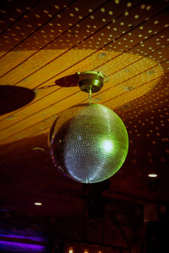 A yellow disco ball reflects artistic lighting at a dance party