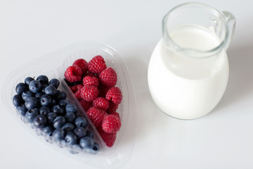 Blueberries and raspberries folded in a transparent box in the form of a heart and a jug of milk. Healthy heart. Vitamins. Diet