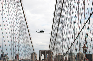 Obraz premium Undefined helicopter flying over Brooklyn Bridge in New York City. USA