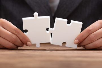 Businessperson's Hand Holding Two Jigsaw Puzzle