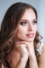 Naklejka premium Gorgeous bride portrait indoor. Beautiful bride with wedding makeup and jewelry on long curly hair.