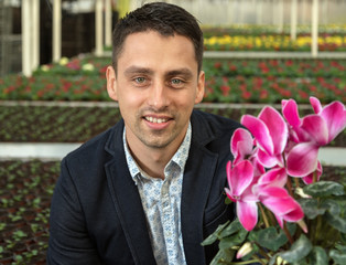 Smiling young man in greenhouse.