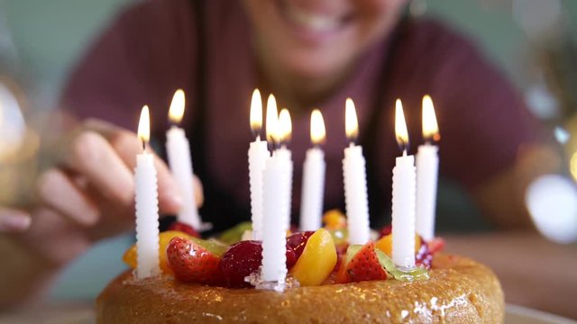 Woman lighting candles on fruity birthday cake 