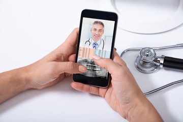 Doctor Video Conferencing With Male Colleague On Cellphone