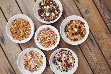 Bowles with different kinds of muesli on wooden background