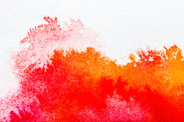 top view of red and orange watercolor spills on white paper