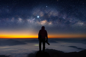 Silhouette of photographer with camera and milky way blackground.