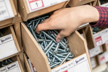 Obraz premium persons hand choose suitable bolt or screw from the crate in hardware store b