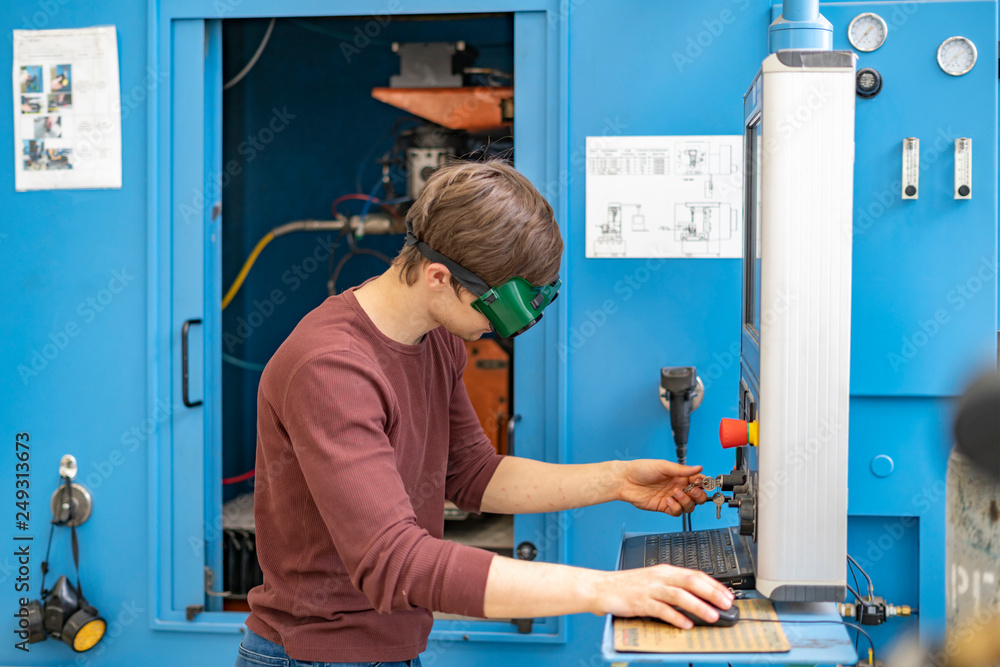 Wall mural worker in protective glasses uses computer panel at the mill b