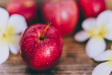 close-up of red apple on wooden table with flowers