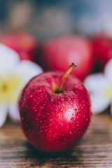 close-up of red apple on wooden table with flowers