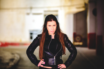 Portrait of young female model dressed in black leather posing casually in an urban setting.