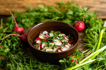 radish salad with green onions in a clay plate on a wooden board
