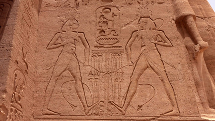 Ancient Egyptian carvings of people and hieroglyphics on the exterior walls of an ancient temple
