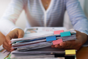 Hands of woman working with stack of paper document to calculate the cost of expenses.