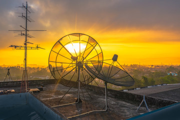 aerial view sunrise on the old satellite dish collapsed on the roof of the tall building.